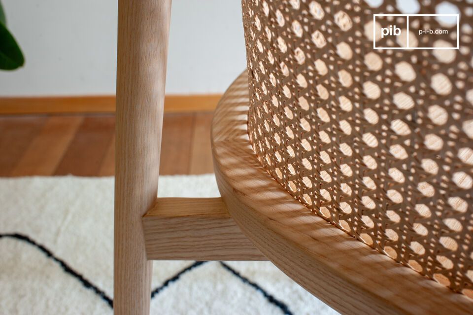 This dining armchair combines a light solid ash base and frame with a wicker cane back